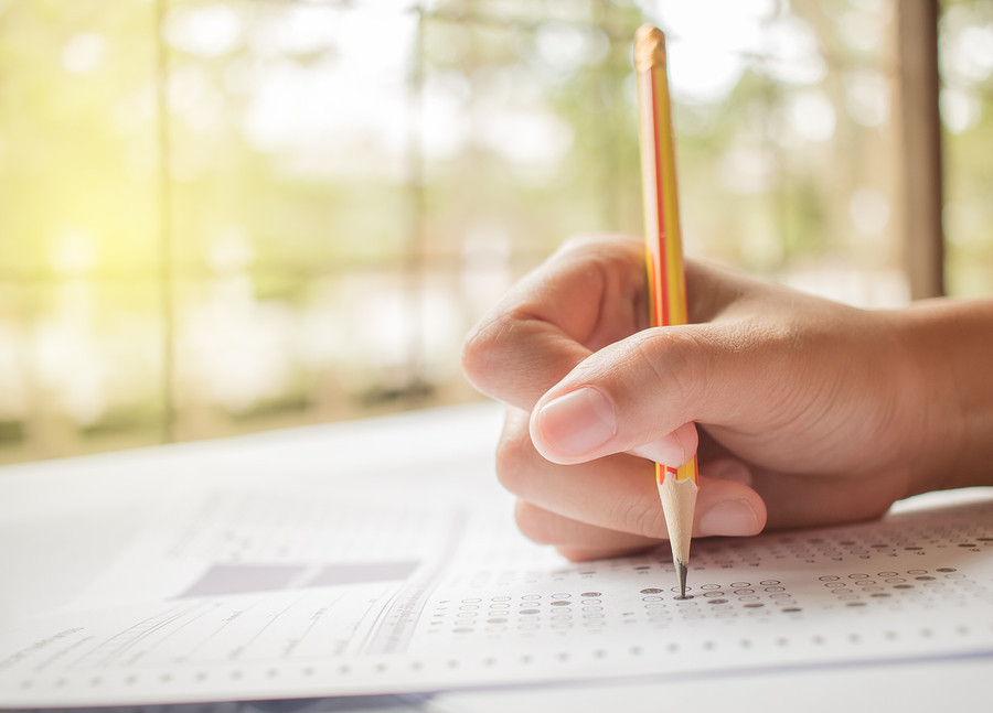 Close-up of a person's hands filling out a multiple choice exam