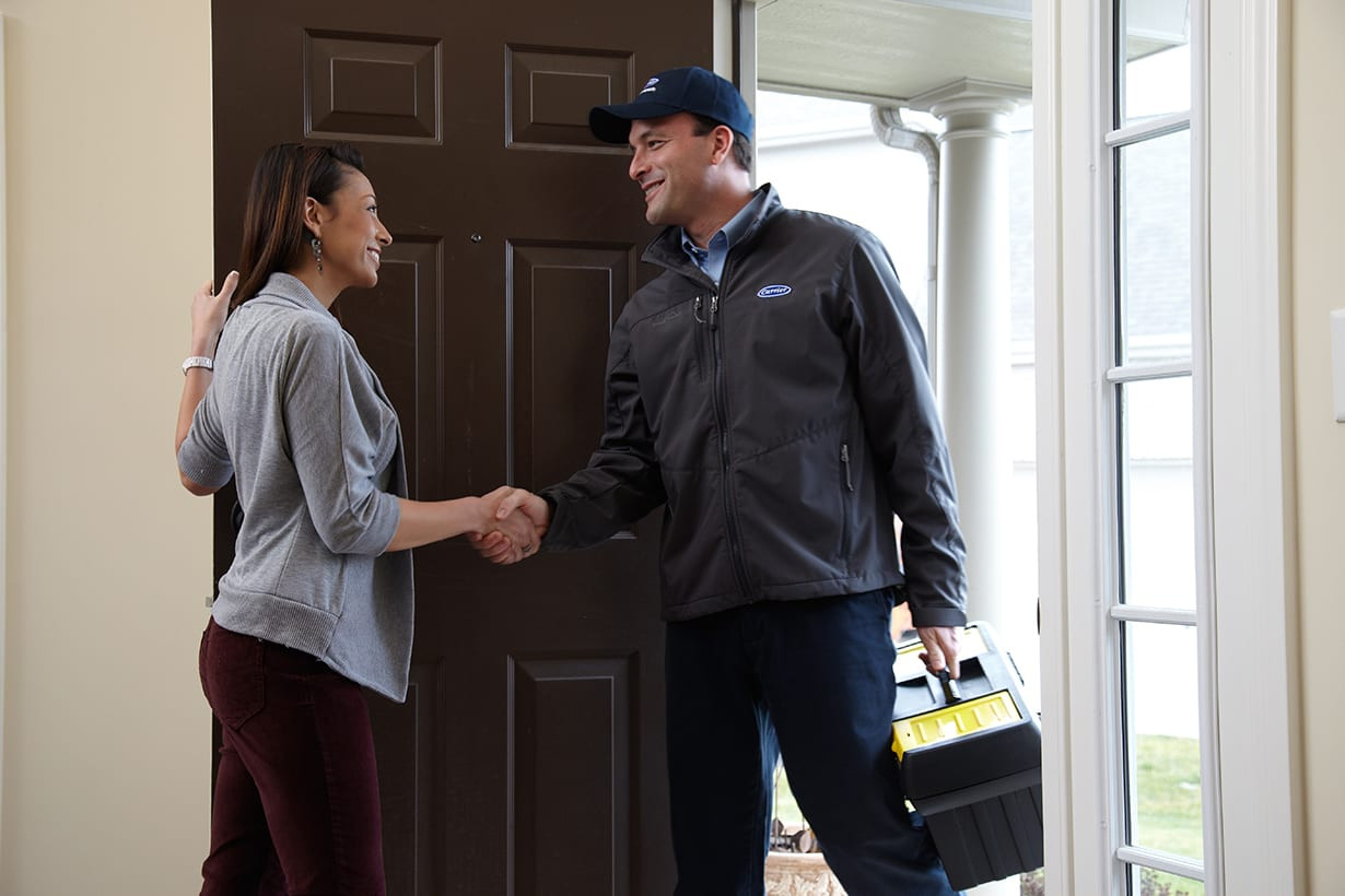 A furnace repair service expert shaking hands with a homeowner after heating repair.