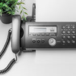 Person using a fax machine at a public location, highlighting accessibility of fax services