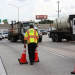Road Ranger truck assisting a motorist with a flat tire on a highway shoulder