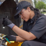 Service member using a flashlight to check a car