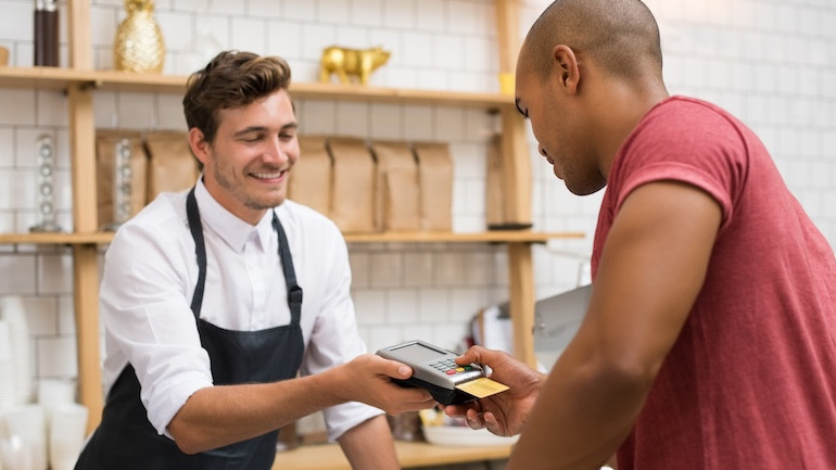Restaurant staff using a credit card terminal for customer payment, emphasizing the point of transaction where service charges and tips are applied.