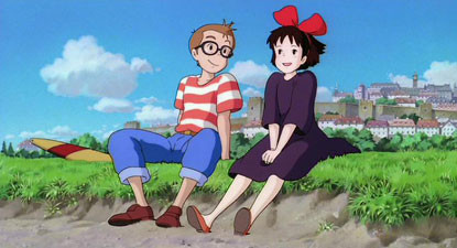 Cosplayer dressed as Tombo from Kiki's Delivery Service, wearing a red and white striped shirt and black glasses, standing next to Kiki.