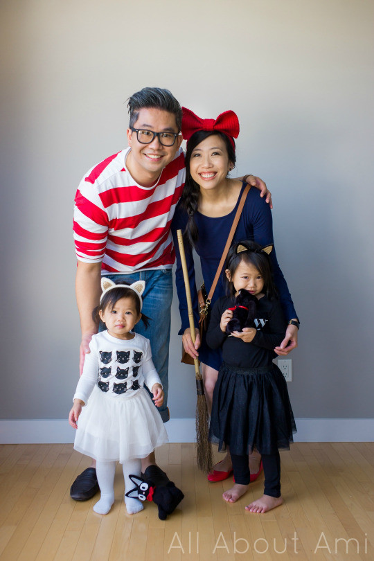 Family dressed in Kiki's Delivery Service cosplay, including Kiki, Tombo, and two children dressed as black cats, posing together.