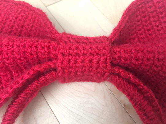 Finished Kiki bow headband with the red bow securely attached to the headband with the middle knot, ready to wear.