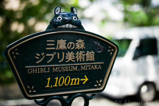 Couple visiting the Ghibli Museum in Japan, posing in the rooftop garden with greenery and architectural elements visible.