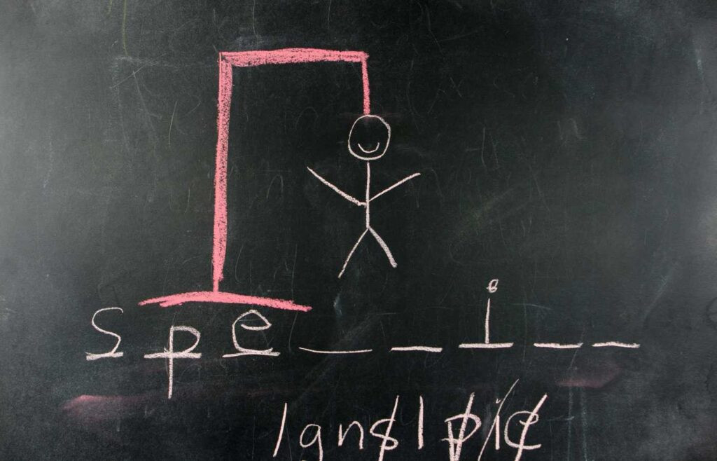 Hangman game drawn in chalk on a blackboard, with the stick figure in a hanging position and blank spaces waiting for letters to be filled.