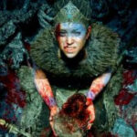 Senua covered in blood and holding skull during Hellblade