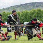 A man tossing a caber at the Highland Games, demonstrating strength and skill