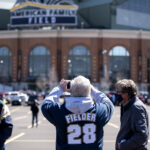 Three fans stand in the parking lot in front of American Family Field