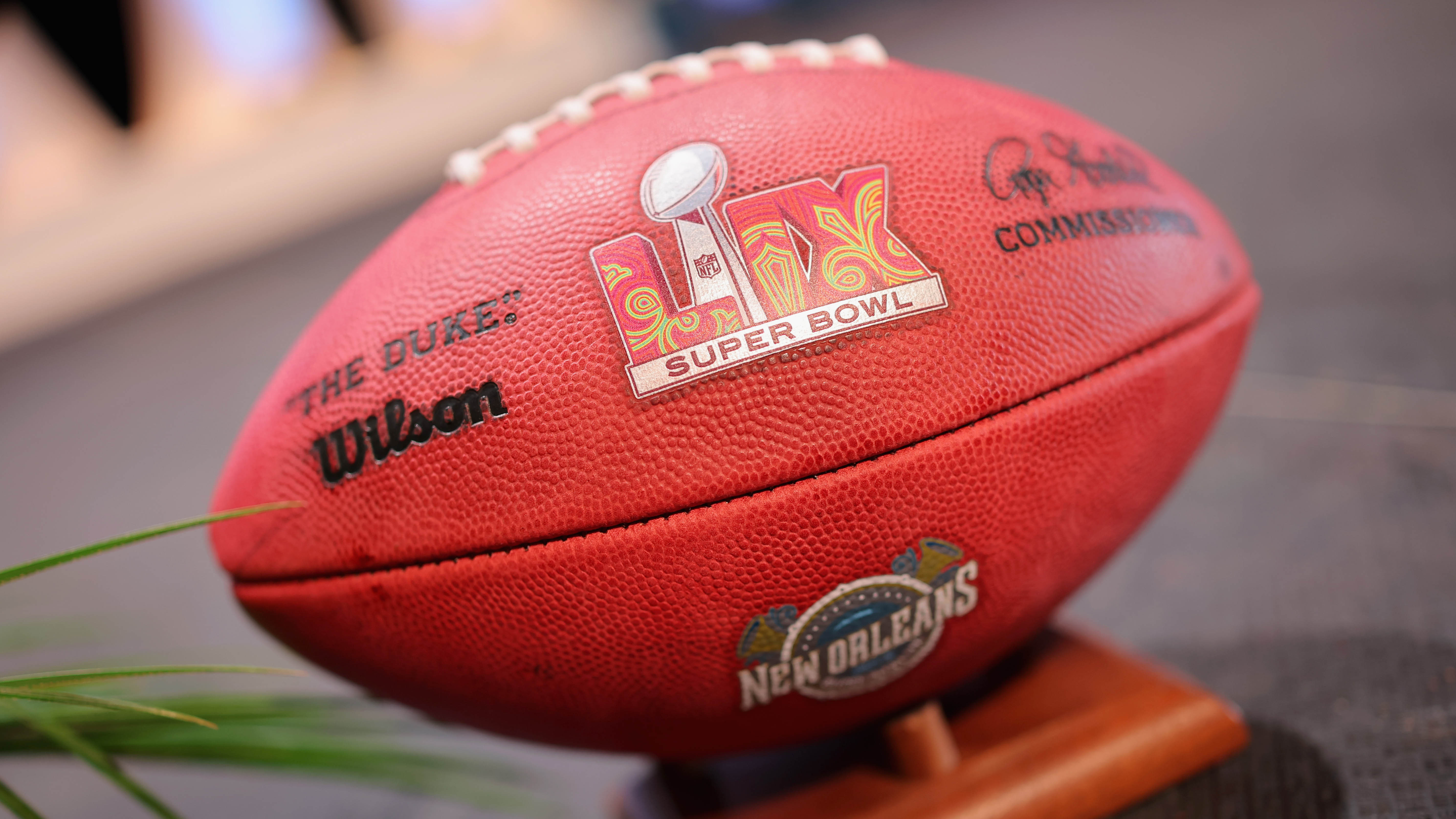 Person sitting on a couch, wearing a Polar fitness tracker, and watching the Super Bowl on TV with excitement, surrounded by game-day snacks.