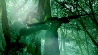 Naked Snake in the jungle holding a gun to his face in one of the best PS2 games, Metal Gear Solid 3: Snake Eater