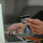 Person holding a credit card while using a laptop, illustrating online payment with financial security