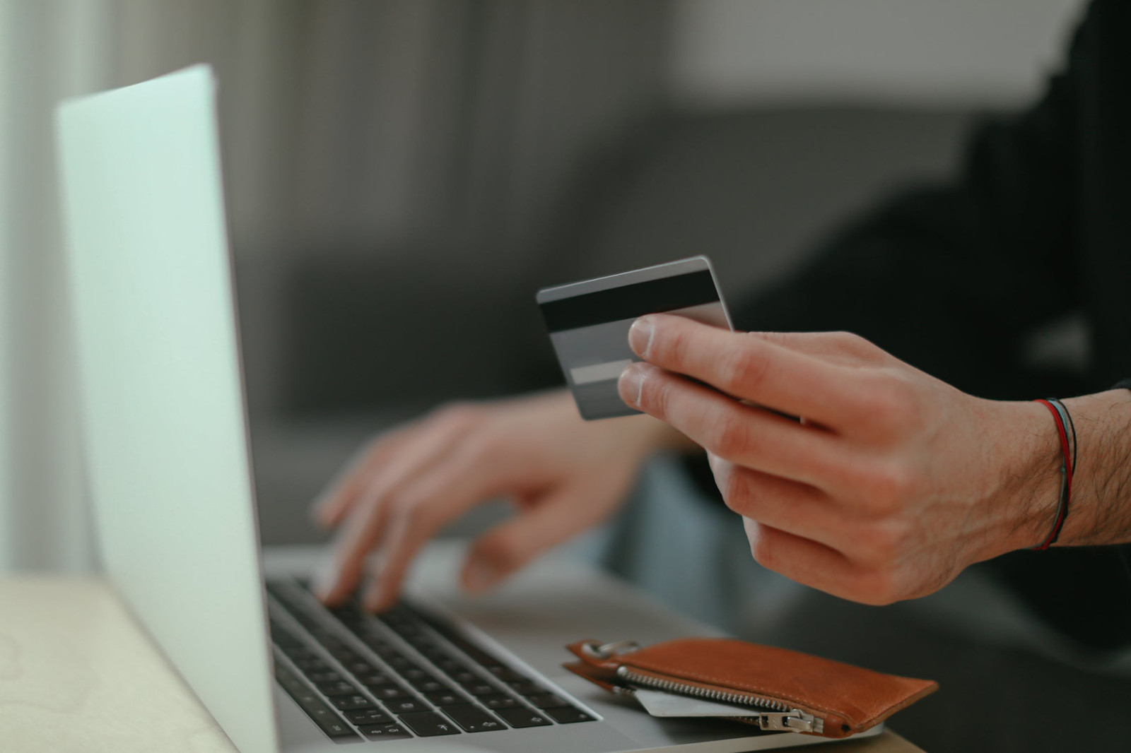 Person holding a credit card while using a laptop, illustrating online payment with financial security