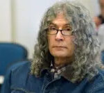 Rodney Alcala during sentencing in 2010, wearing a denim jacket and checked shirt, his long curly grey hair visible