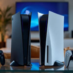 Two video game consoles with their controllers placed on a table in a modern living room