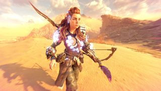 Horizon Forbidden West screenshot of Aloy in power armor, walking across a barren desert landscape.