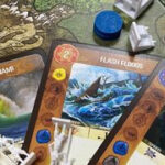 A selection of game pieces from Spirit Island, including spirit boards and invader miniatures
