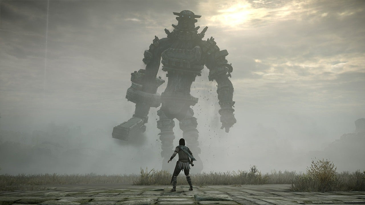 A person stands in front of a large stone colossus in Shadow of the Colossus