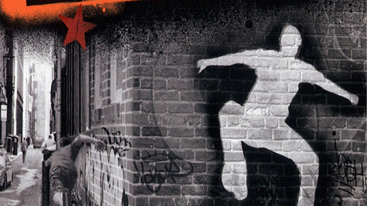A graffitied skaterboarder performing a trick on a wall