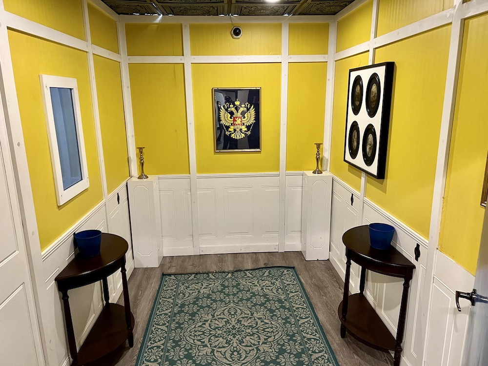 A hallway with yellow walls and candlesticks pedestals.