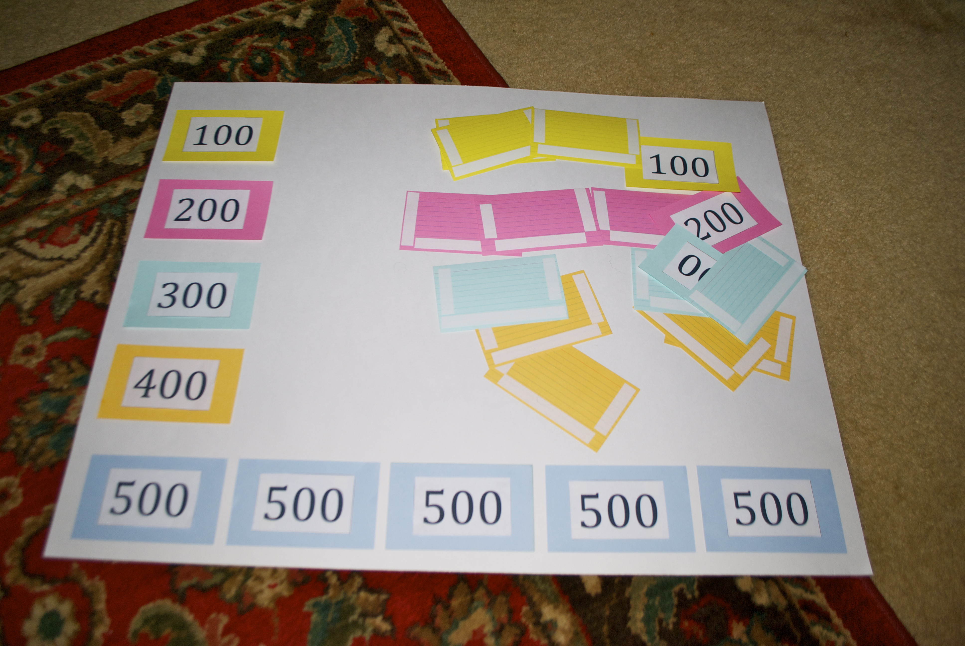 Index cards with printed numbers being glued for a Jeopardy game