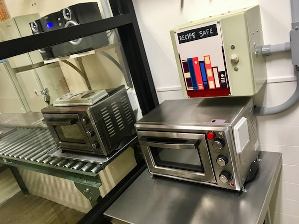 In-game: a small oven in a kitchen, above it a box labeled 