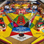 Solid State Pinball Supply alt: Inside Solid State Pinball Supply, a vibrant scene unfolds with numerous vintage pinball machines lined up, their colorful lights and designs creating an inviting atmosphere for gamers.