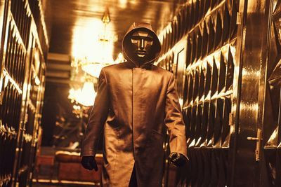 Man wearing a golden mask walks down a hall in squid game season 1