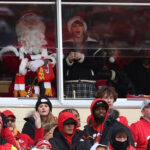 Taylor Swift watching the Christmas Raiders game, wearing a Santa hat and a bow in her hair.