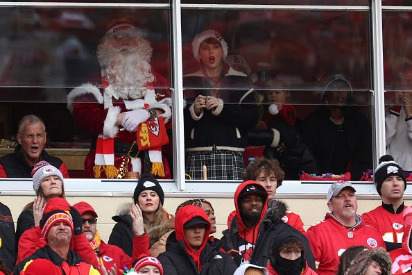 Taylor Swift watching the Christmas Raiders game, wearing a Santa hat and a bow in her hair.