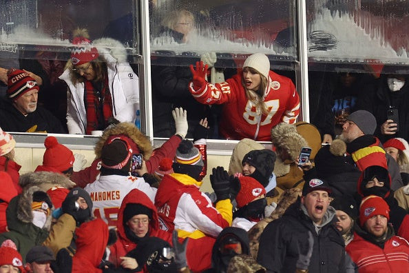 Taylor Swift celebrating with fans at the Dolphins game, bundled up in a warm jacket.