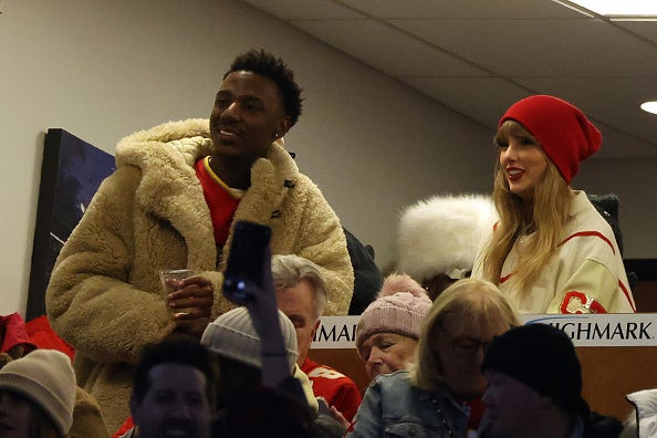 Taylor Swift watching the Bills game with Jerrod Carmichael, wearing a beanie and jacket.