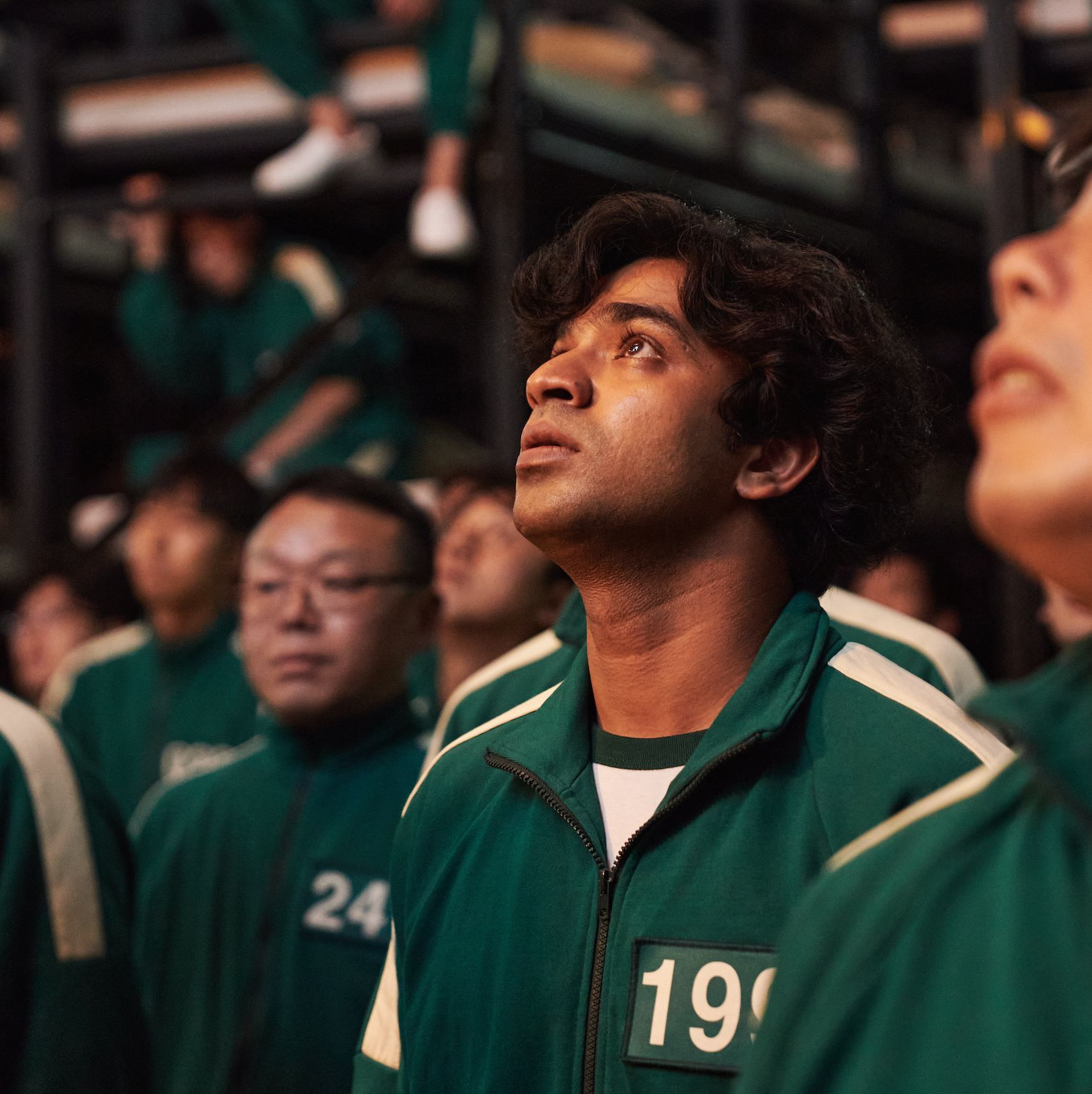 Anupam Tripathi as Ali Abdul, or player 199, wearing a green suit and looking up in squid game season 1