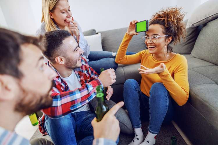 group of friends playing heads up charades game with smartphone