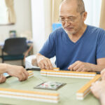 Elderly people playing mahjong in the recreation room of a long-term care facility