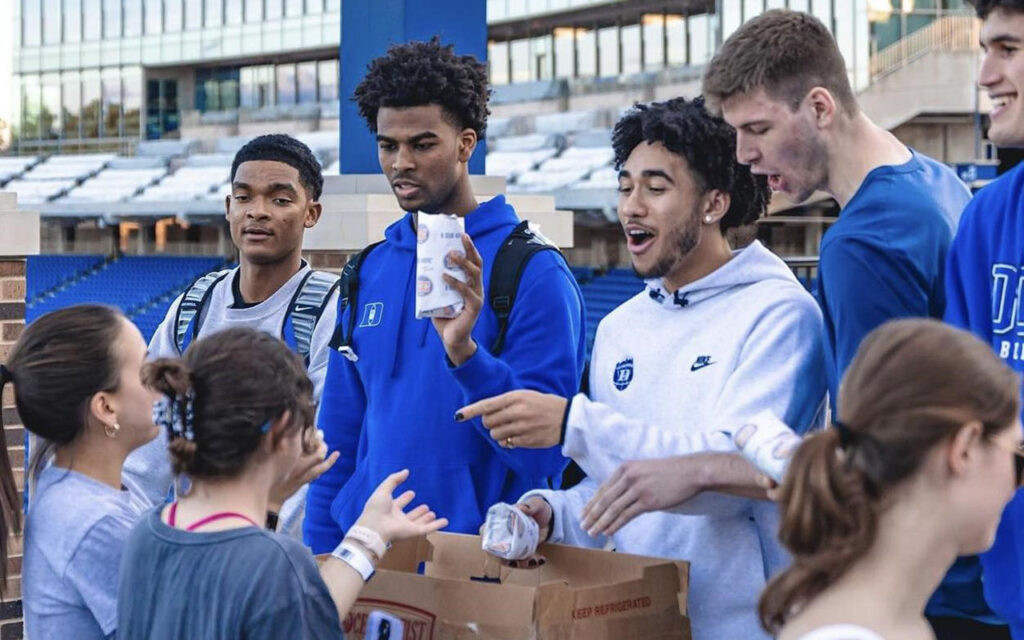 Duke basketball team members handing out meals to campers during the Duke-UNC game campout.