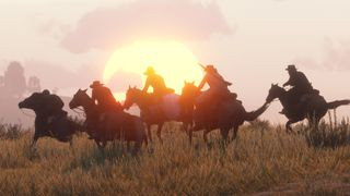 A group of cowboys ride across a grassy plain as the sun sets in the background in Red Dead Redemption 2