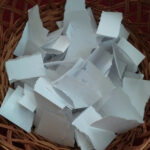 Slips of paper in a basket labeled Name Game, representing the randomness and fun of the celebrity name game
