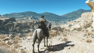 Metal Gear Solid 5: Phantom Pain screenshot of a man sitting astride a white horse in a sandy, desert-like environment.