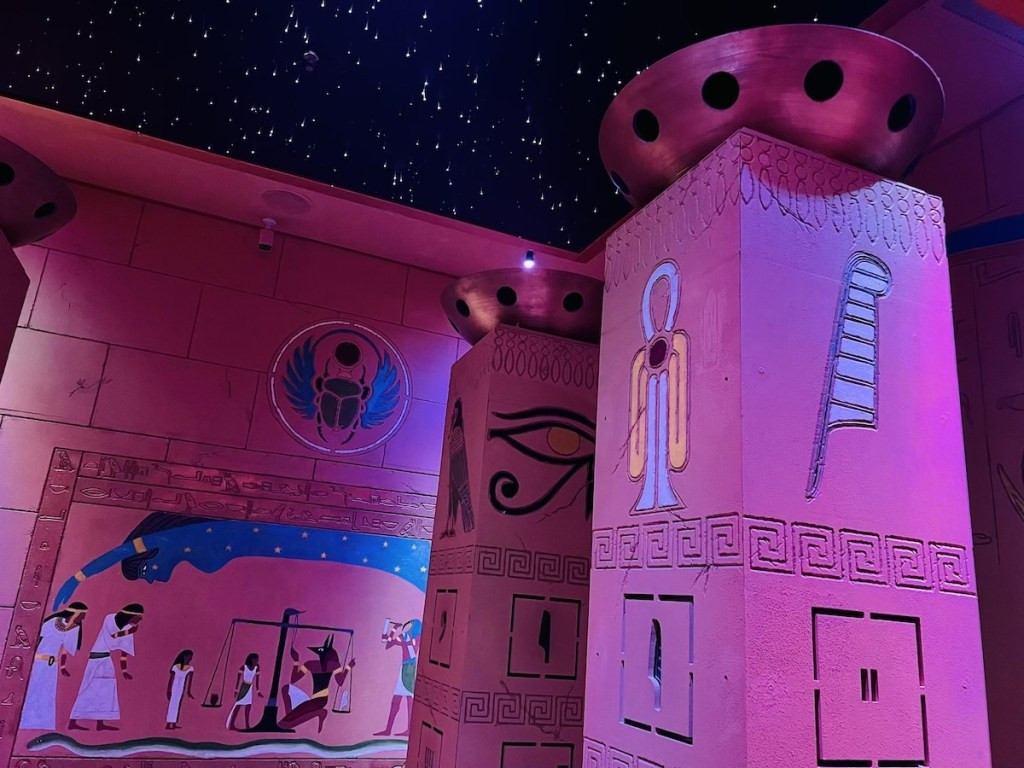 Pillars inside the entry way to an Egyptian tomb with a beautiful starry night sky overhead, emphasizing the enchanting setting.