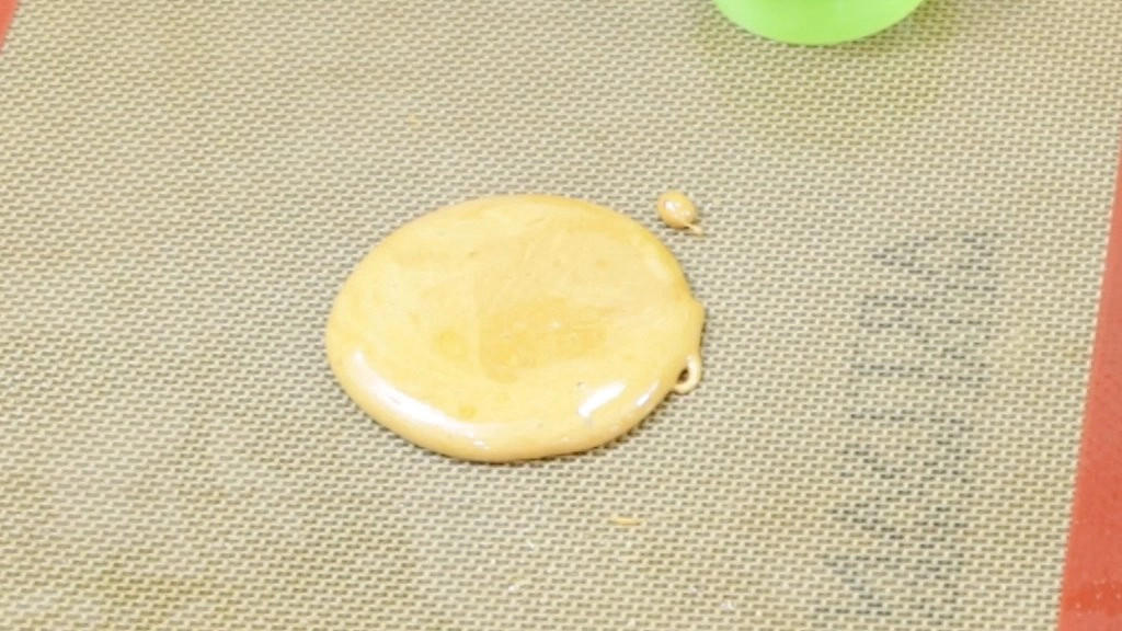 Round pile of dalgona candy cooling on a silicone mat.