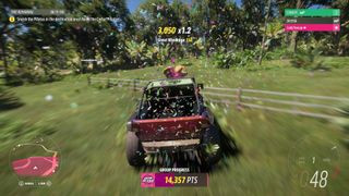 A car racing through a grassy barn in Forza Horizon 5, an Xbox exclusive, highlighting the game's stunning open-world environment
