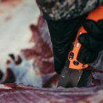 Hunter skinning a deer carcass in the field to cool game meat quickly and prevent spoilage.