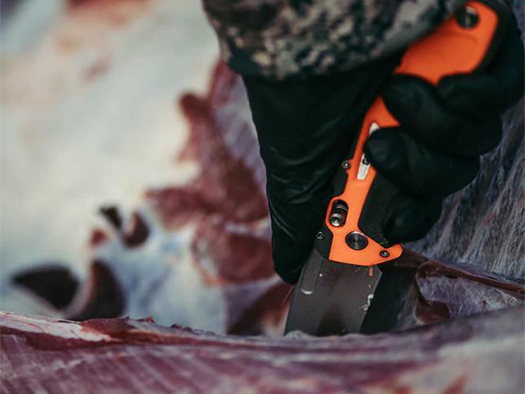 Hunter skinning a deer carcass in the field to cool game meat quickly and prevent spoilage.