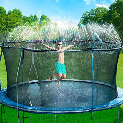 A child in blue swim trunks bounces on a trampoline with sprinklers spraying water from the top. 