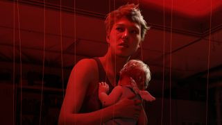 A screenshot of a woman holding a baby in the upcoming PS5 game, Death Stranding 2.