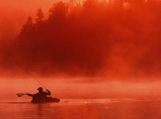 Woods Canyon Lake in Arizona with anglers fishing from the shore and boats amid pine trees and clear water.