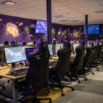 Many gaming PC lined up with gaming chairs.