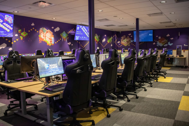 Many gaming PC lined up with gaming chairs.